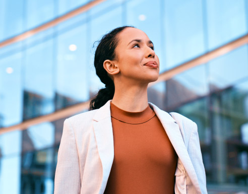 Jeune actif en tenue professionnelle devant un bâtiment moderne.