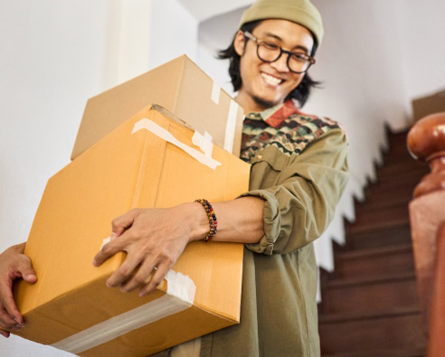 Jeune adulte portant des cartons lors d’un déménagement.