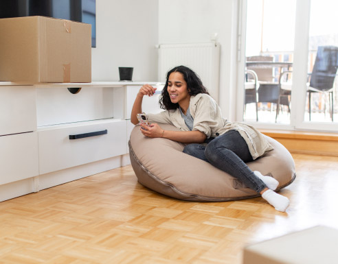 Jeune adulte allongé avec son smartphone dans un appartement fraîchement aménagé