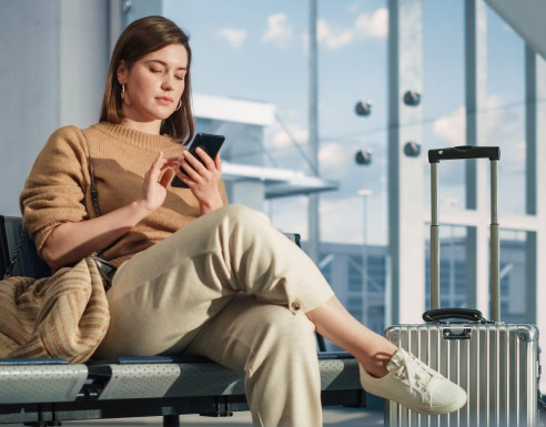 Voyageuse assise à l’aéroport avec sa valise, préparant son voyage à l’étranger